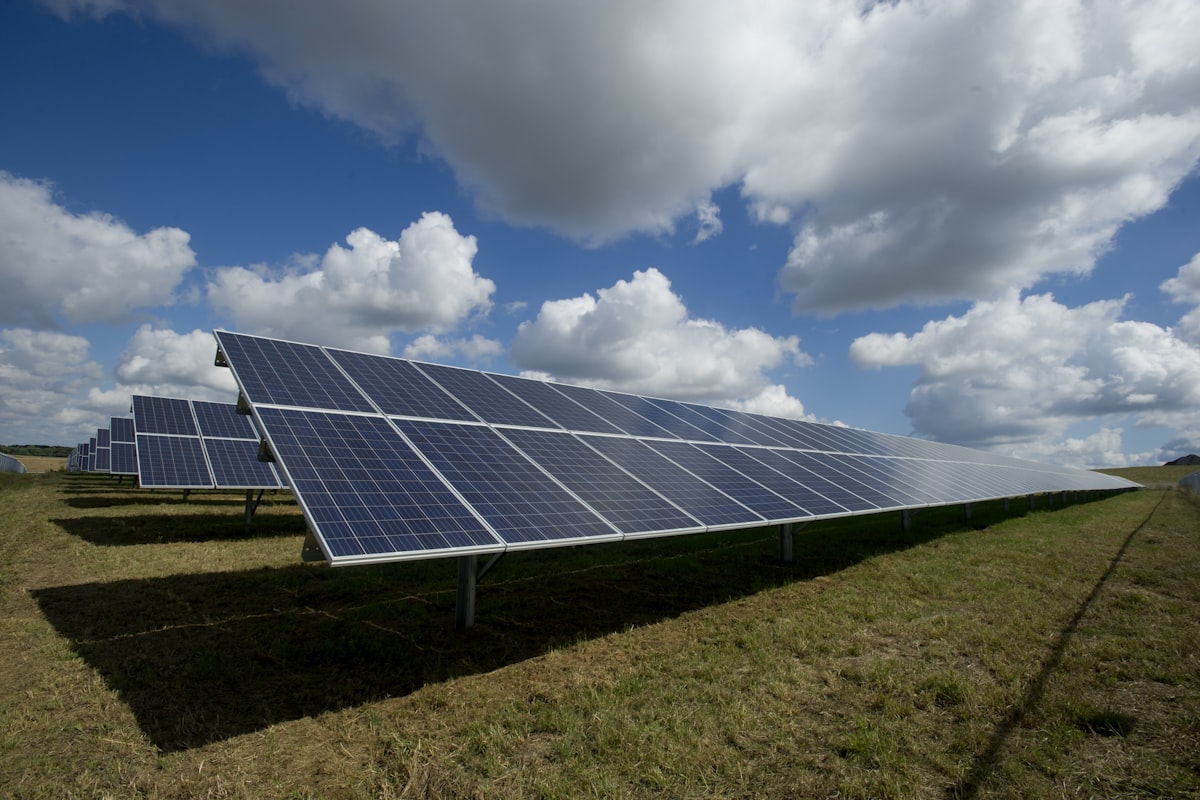 Utility-scale solar panel array under a wide sky feeding battery storage that stabilizes the power grid