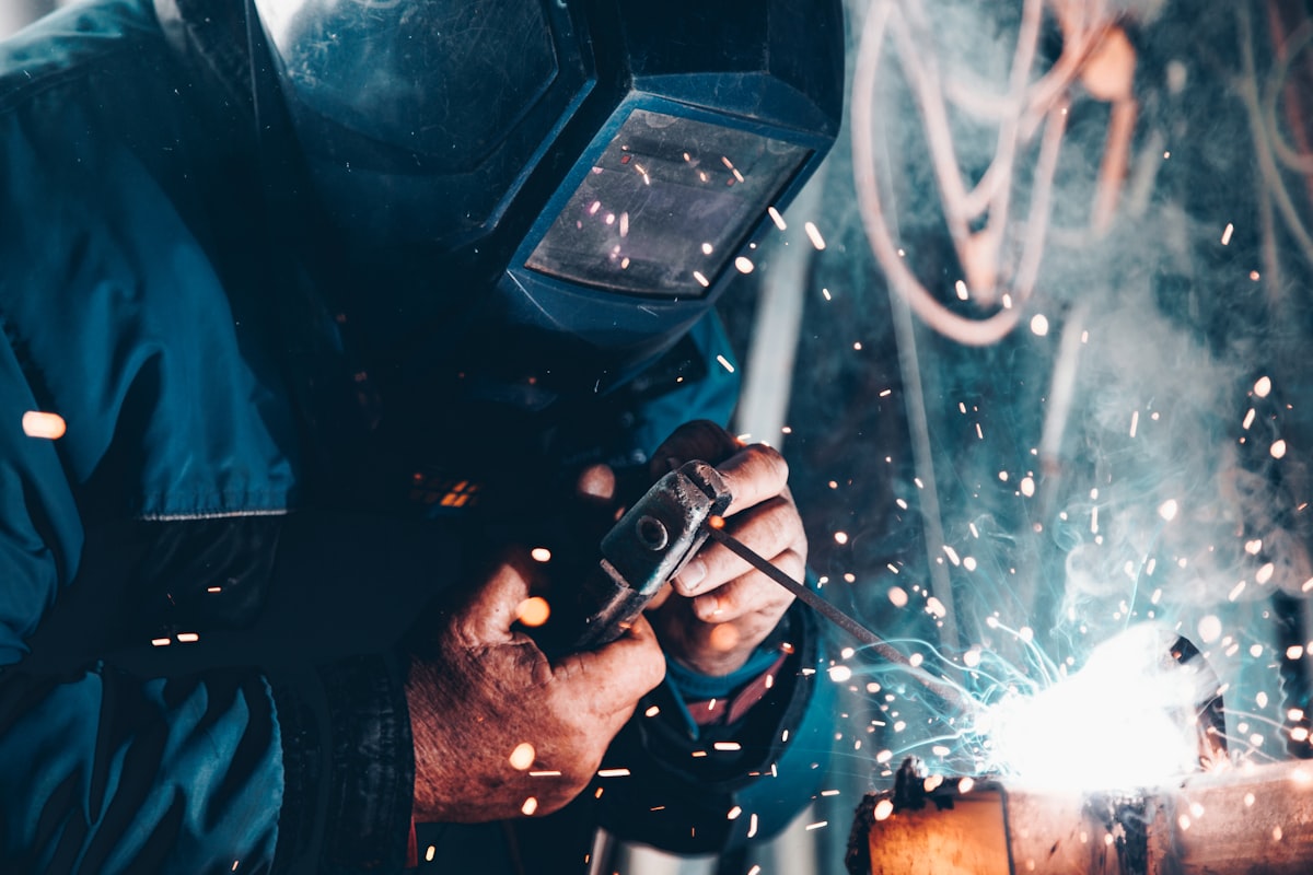 Manufacturing worker welding on a factory floor with sparks flying